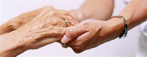 Mãos de cuidador e idoso se segurando demonstrando carinho e cuidado
